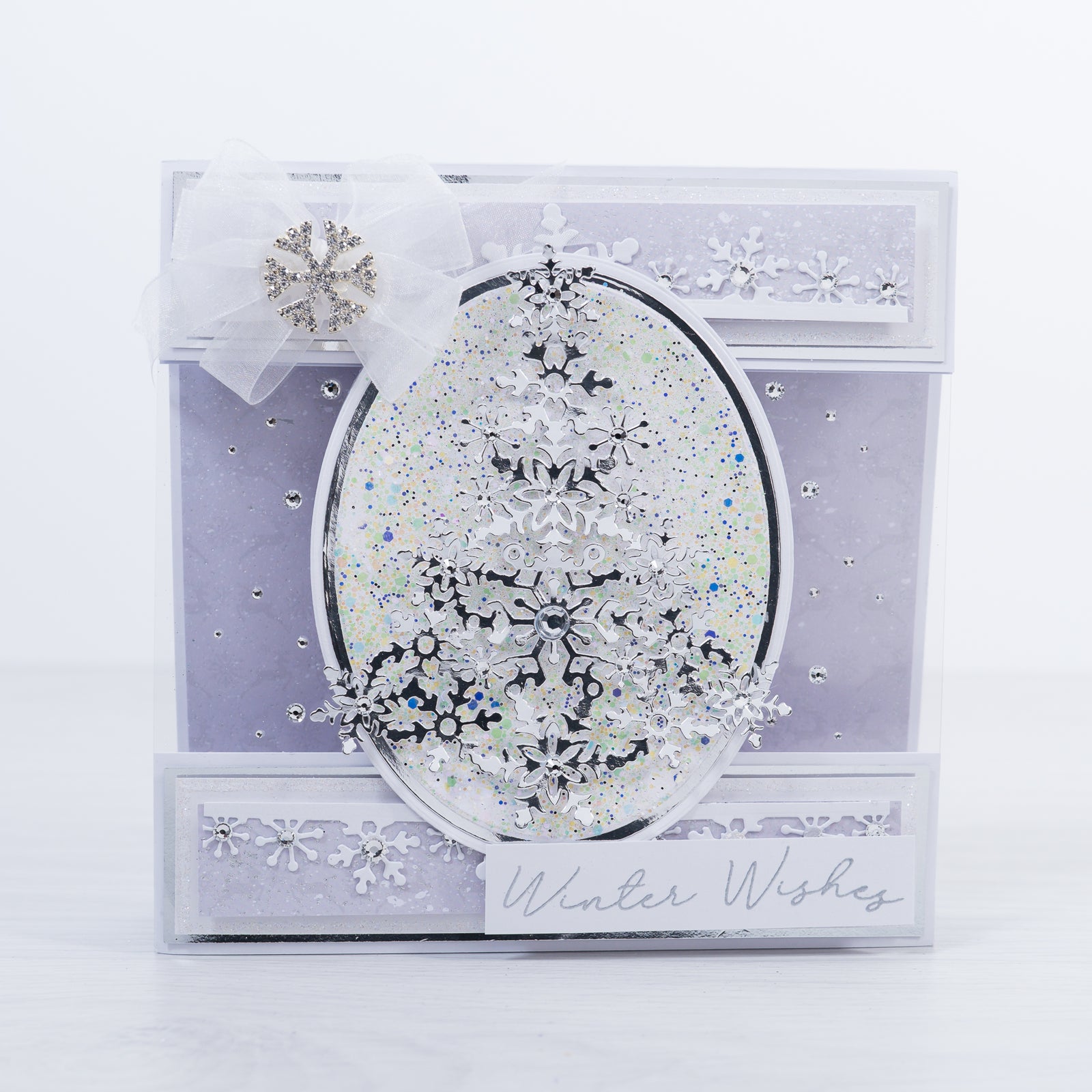 Our free Winter Wishes card making tutorial shows you step-by-step how to make this gorgeous silver mirror card Christmas Tree stamp featuring lovely lilac and white card layers with glitter snowflake details